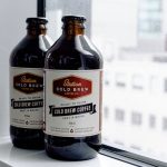 Two glass bottles of cold brew coffee placed on a window ledge, ready to drink.