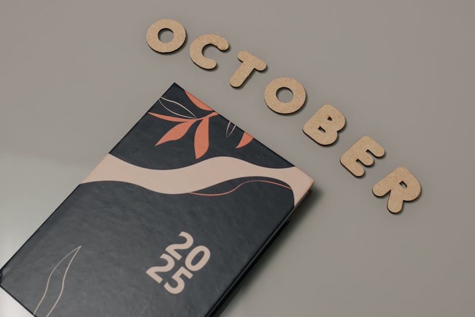 A sleek planner with October letters and 2025 date, set on a neutral surface.